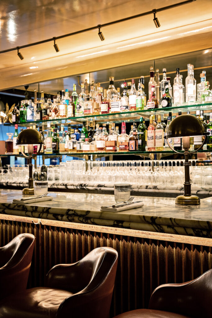 Elegant bar at Aux Prés restaurant in Saint-Germain-des-Prés, Paris, showcasing a luxurious ambiance with a marble countertop and fine spirits.