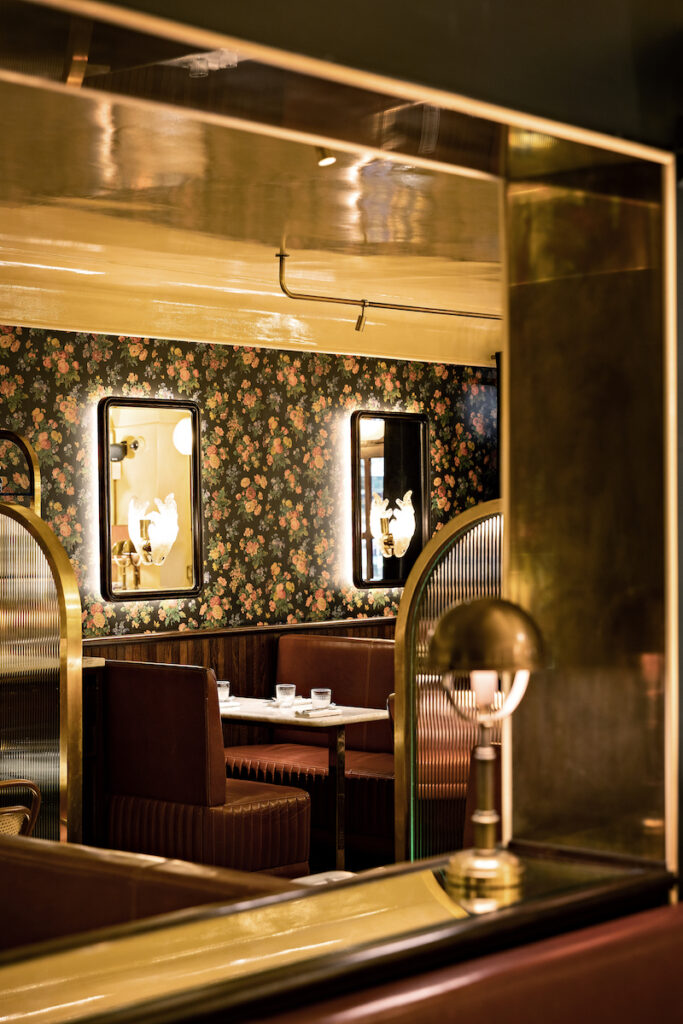 Cozy dining area at Aux Prés restaurant in Paris with floral wallpaper, soft lighting, and plush seating for an intimate setting.
