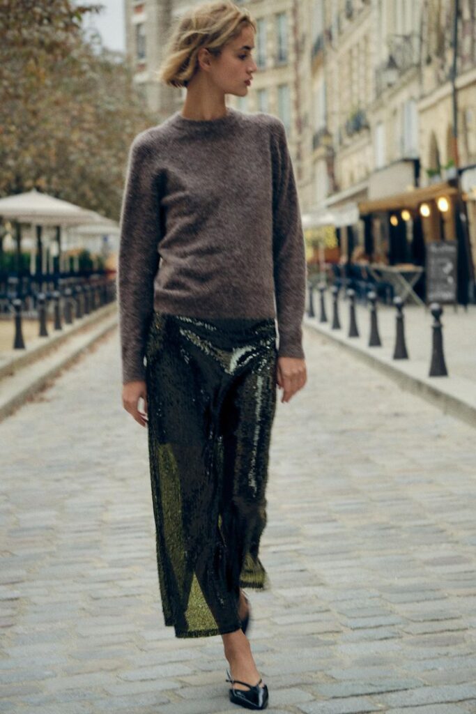 Woman in Paris wearing a green sequin skirt and cozy sweater, showcasing a balanced holiday look with one bold statement piece.