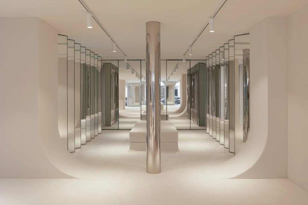 Courrèges François Iᵉʳ boutique in Paris featuring monochrome interiors, mirrored accents, and soft carpeting.
