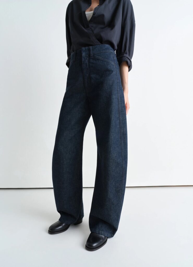 Close-up of Lemaire SS25 high-waisted curved indigo jeans paired with a relaxed black shirt, highlighting minimalist Parisian style.