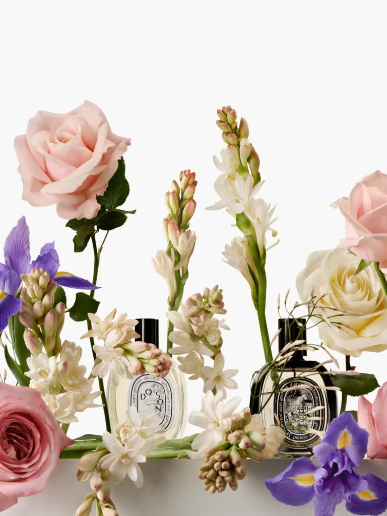 Diptyque Do Son and Eau Capitale perfume bottles with fresh flowers in a soft, romantic setting. French perfume brands.