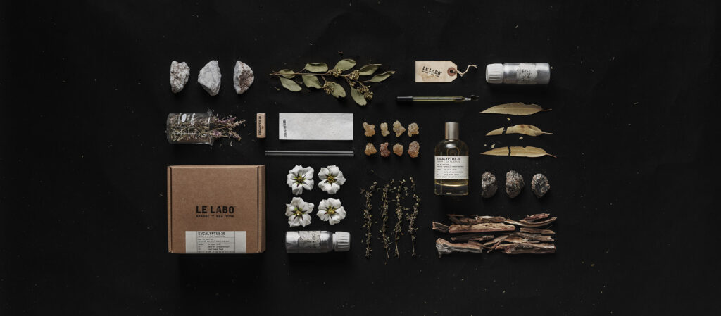 Le Labo Eucalyptus 20 perfume bottle displayed alongside natural ingredients on a dark background. French perfume brands.