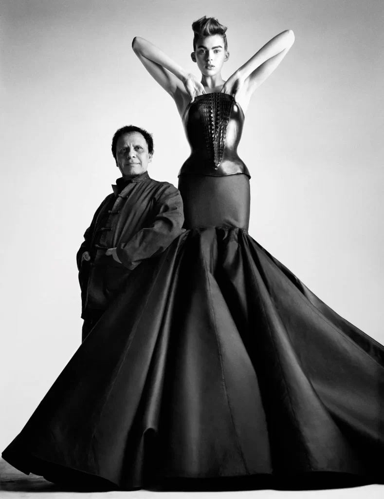 Azzedine Alaïa standing next to a model in a dramatic corset dress.