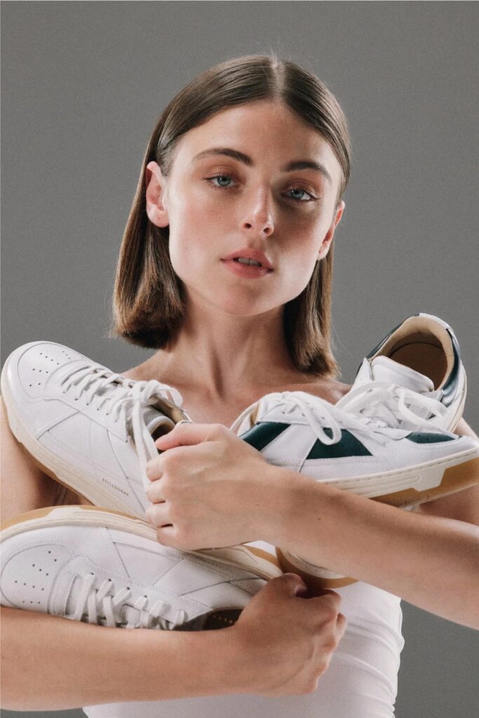 A woman holding multiple pairs of Belledonne sneakers, a high-end minimalist choice among French sneaker brands.
