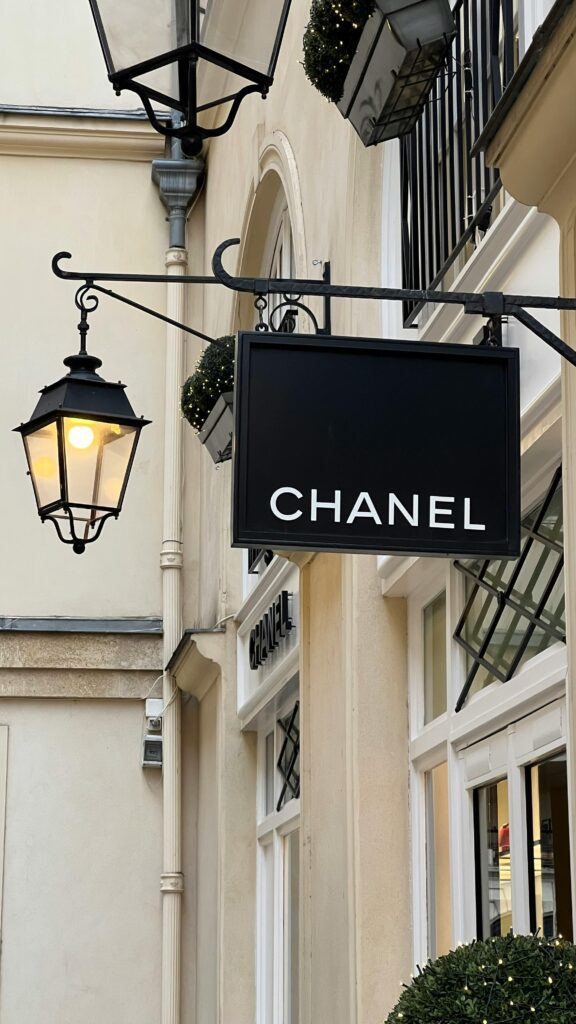The entrance to a Chanel boutique in Paris, featuring classic black and gold signage. What to buy in Paris.
