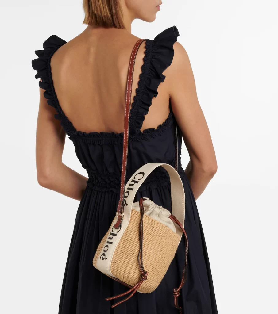 Chloé Woody Basket Bag, a small raffia handbag with a canvas logo strap and leather trim.