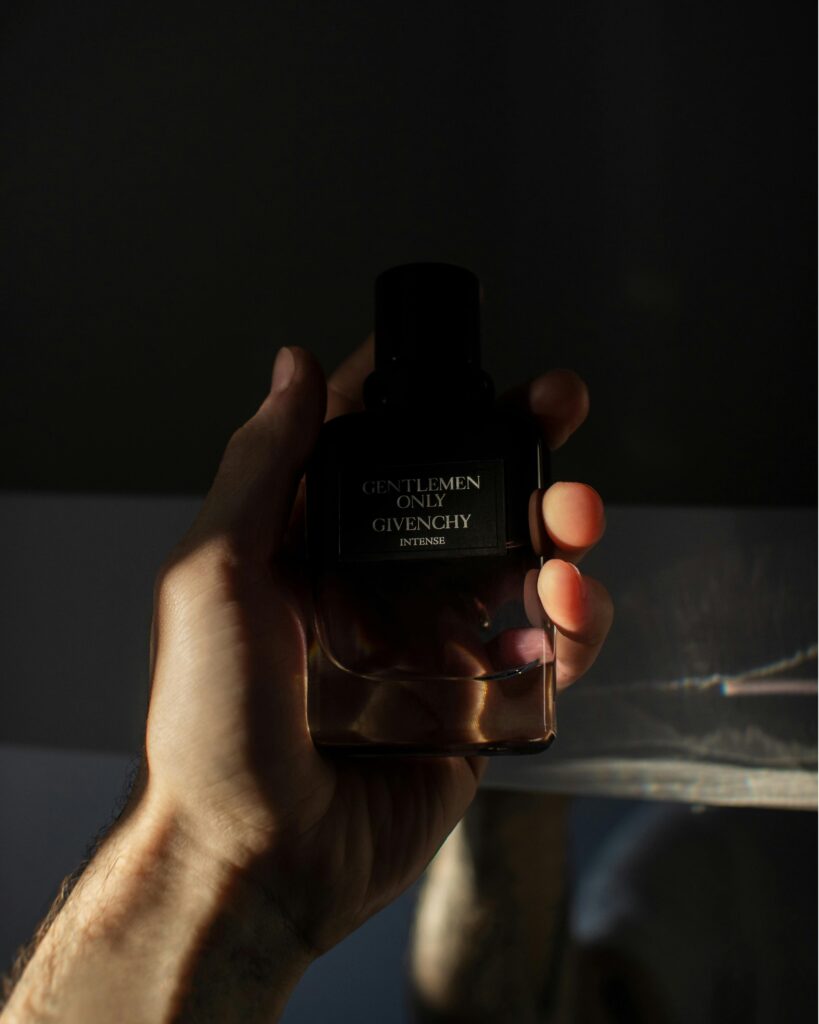 A hand holding Givenchy "Gentlemen Only Intense" perfume in dim lighting. French perfume brands.