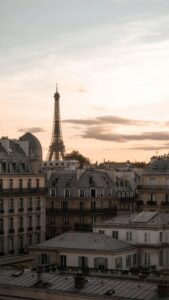 The Eiffel Tower overlooking Paris rooftops at sunset, symbolizing the City of Light.