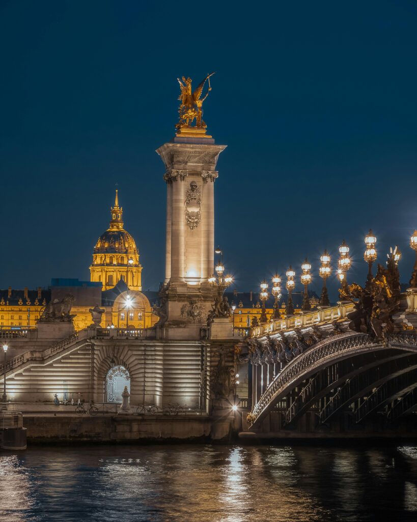 The Pont Alexandre III bridge glowing at night with golden lights, showcasing why Paris is called the City of Light.