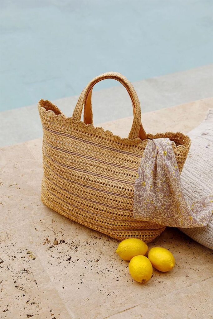 Vanessa Bruno raffia tote placed near a poolside with a scarf detail.