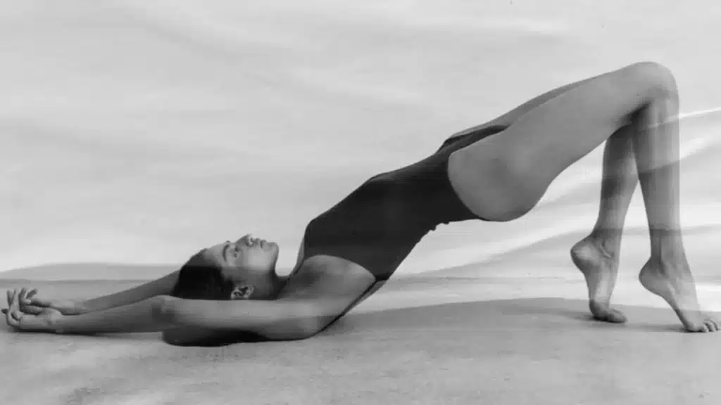 Woman in a Pilates bridge pose, demonstrating low-impact strength training. best workout classes in Paris.