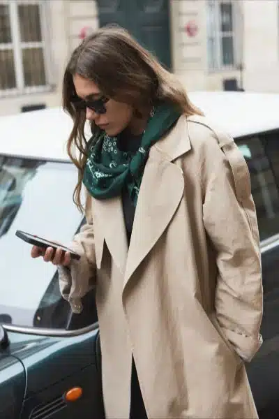 A deep green silk scarf styled with a neutral trench coat for an effortless look.