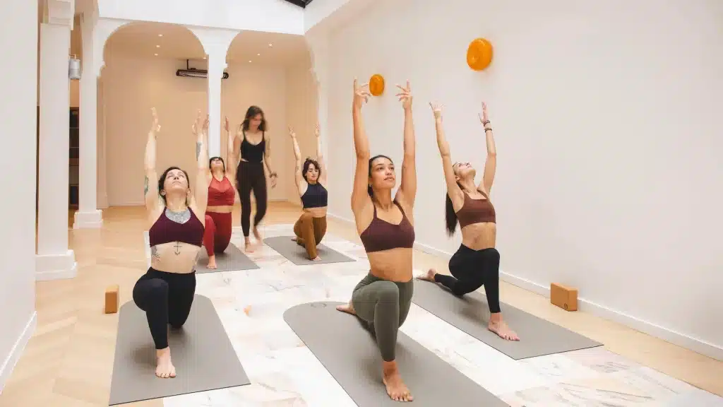 Women practicing prenatal yoga in a serene, sunlit studio at Mama Yoga in Paris. best workout classes in Paris.