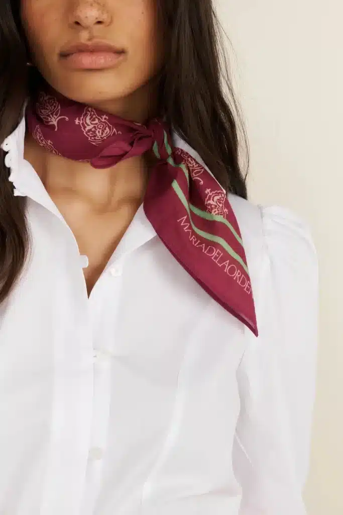 A burgundy silk scarf from Maria de la Orden, styled with a crisp white shirt.