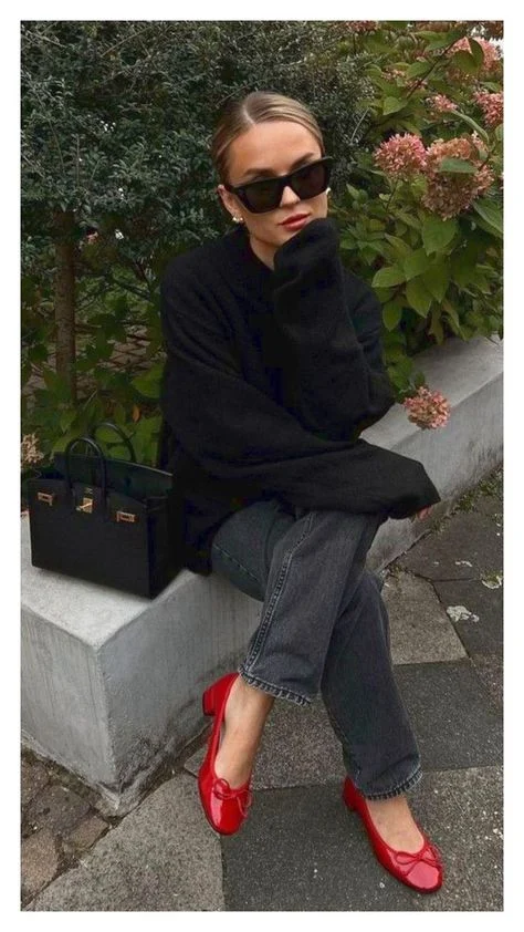 What to wear in Paris in the spring – red ballet flats paired with dark denim and a black sweater.