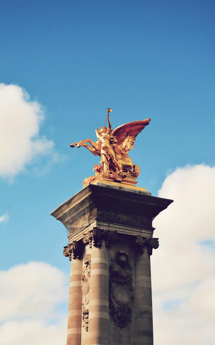 Gilded female allegorical statue of Fame blowing trumpet on Pegasus
