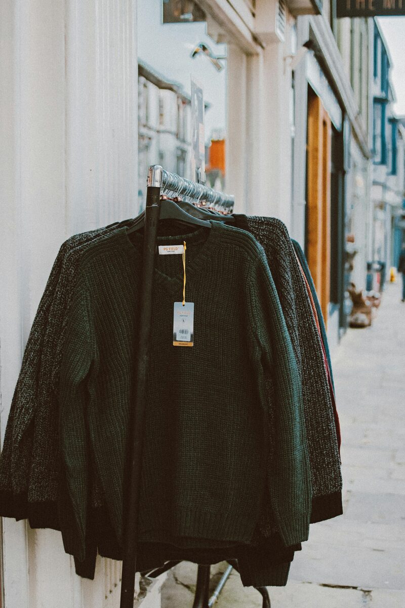 A rack of vintage sweaters outside a Paris shop, showcasing French thrift fashion
