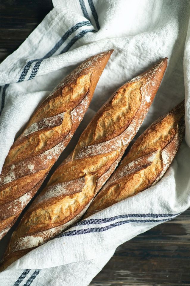 Fresh French baguettes resting on linen cloth, showing part of how to eat like a French woman.