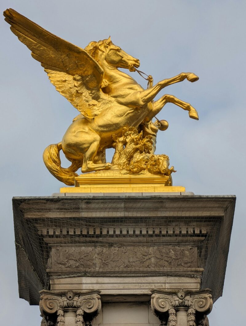Detailed view of golden Pegasus rearing on a sculpted pedestal