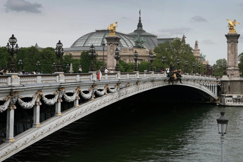 Couple walking across Pont Alexandre III with ornate details and Grand Palais in background