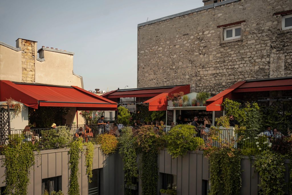 Leafy rooftop terrace with red awnings at The Shed in Paris