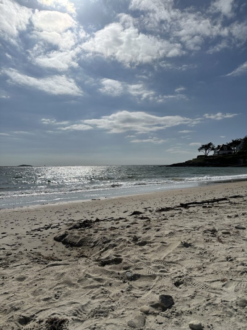 Peaceful sandy beach with gentle waves in Brittany, France, under a bright summer sky
