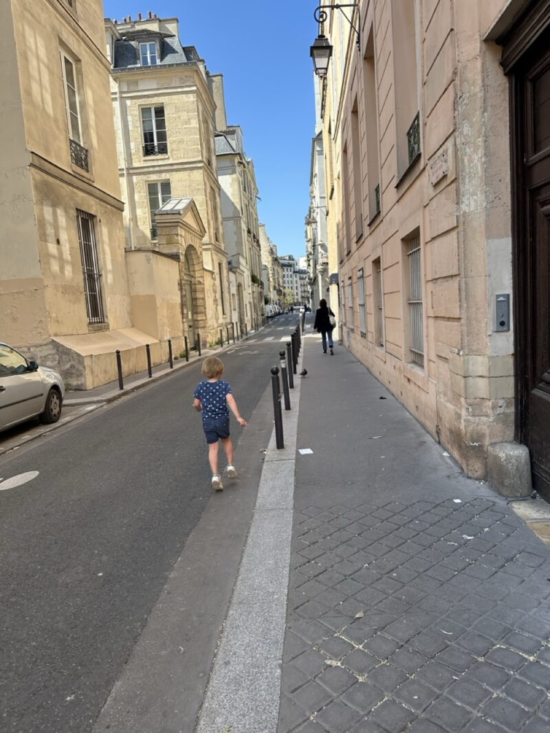 A quiet street in central Paris with one person walking, typical of August when locals leave the city