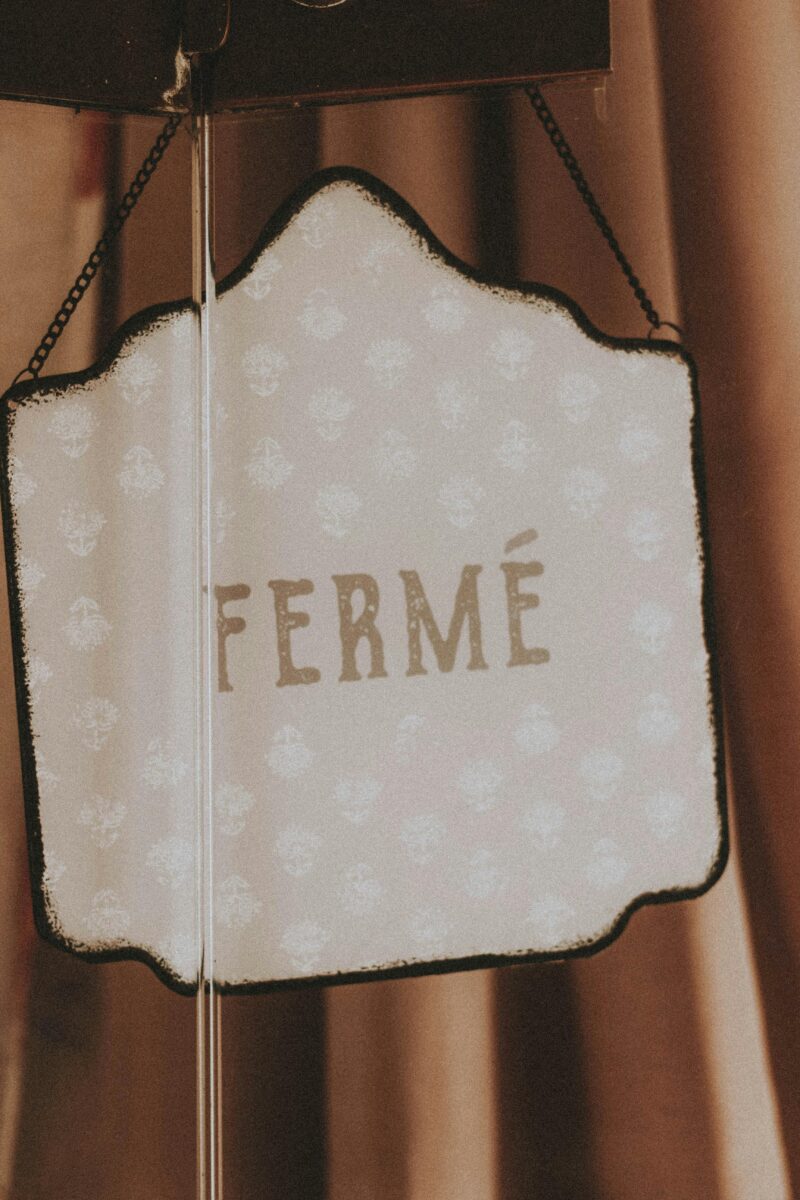 French sign reading "fermé" hanging in a closed shop window in Paris