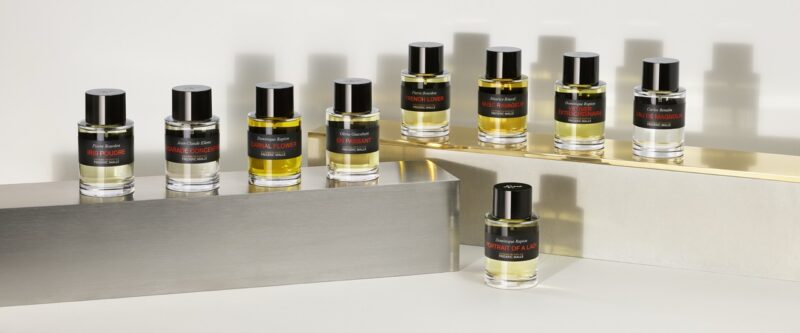 A selection of Frédéric Malle perfumes arranged on metallic and gold platforms