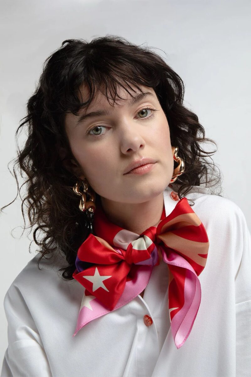 Model wearing a vibrant red silk scarf with star prints by French brand Elise Chalmin