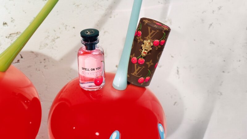 Louis Vuitton perfume Spell On You displayed with a cherry-themed LV case