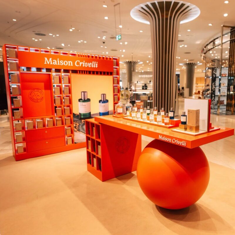 Bold orange Maison Crivelli fragrance display in a Parisian department store. french perfume shops in paris