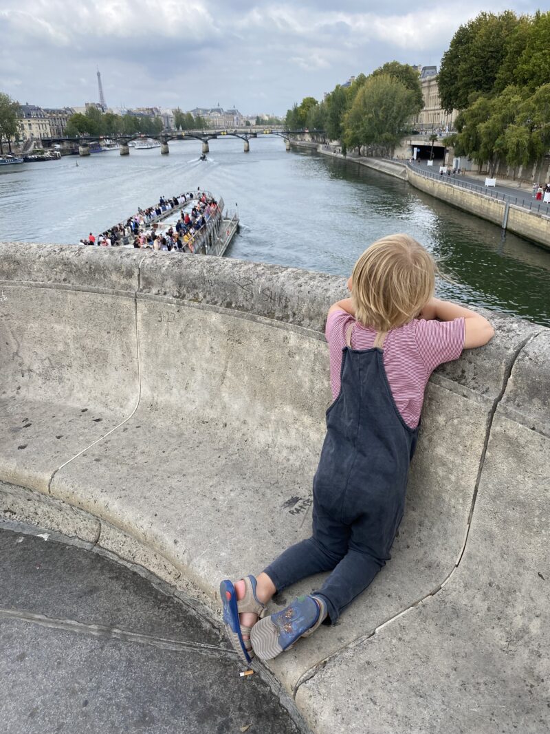 Boy watching a Bateau Mouche from Pont Neuf Paris bridge in August in Paris during August
