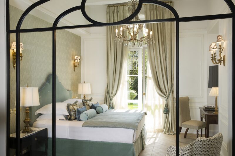 Elegant hotel room at Relais Christine with light green curtains and chandelier