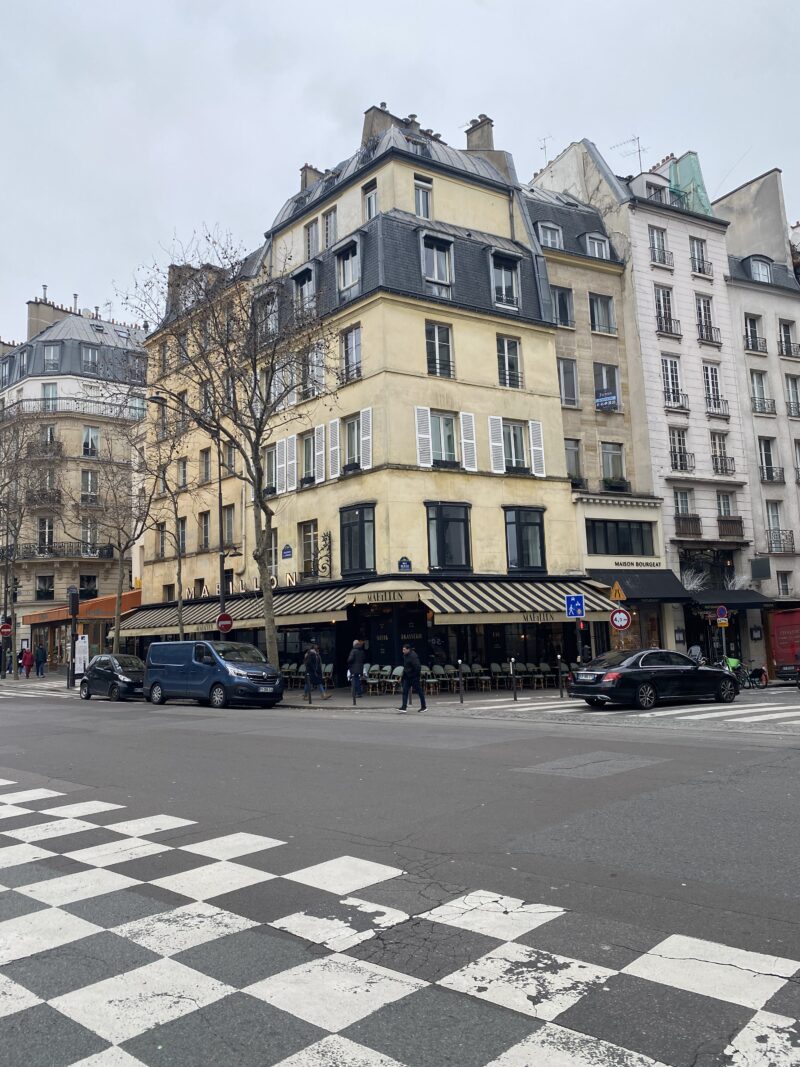 Corner café in Paris with striped awning and winter trees