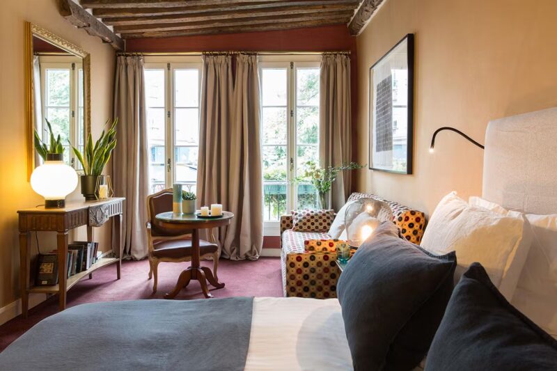 Elegant Parisian hotel room with wooden beams, velvet carpet, and natural light in March