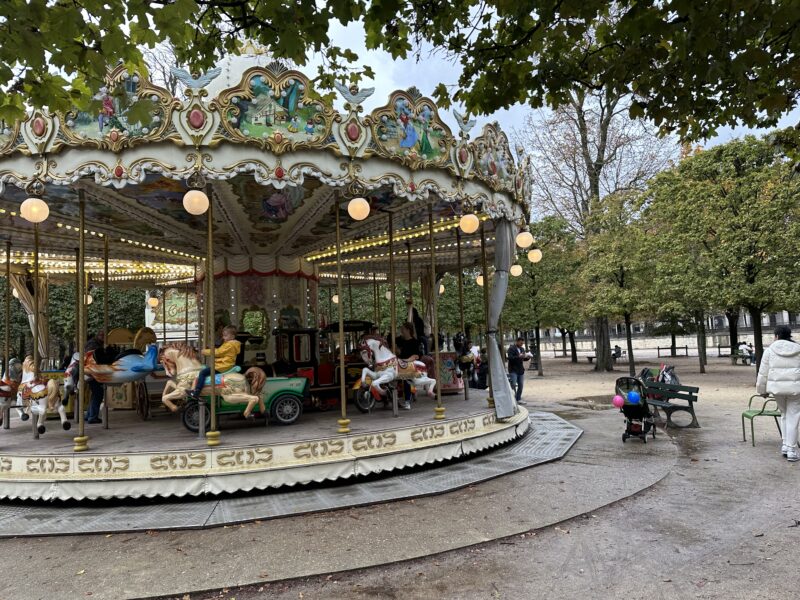 Classic Paris carousel in Tuileries with autumn trees in the background.