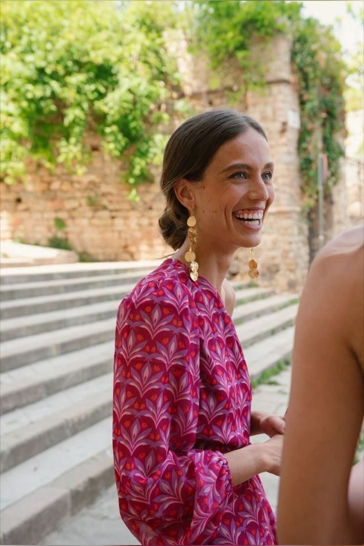Smiling woman in a printed dress with oversized gold earrings