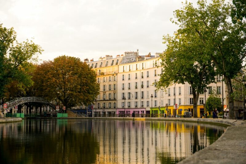 Tranquil view of Canal Saint-Martin in Paris with tree-lined banks and a footbridge