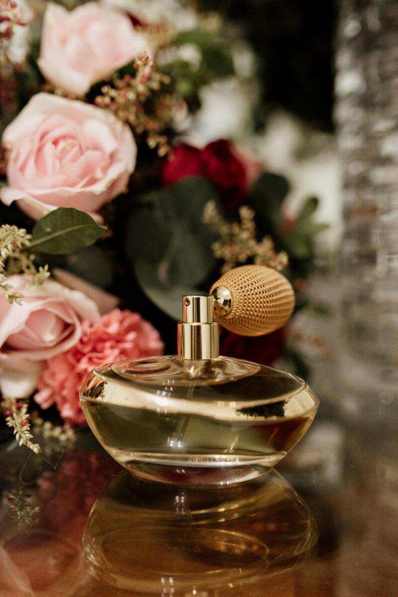 Antique perfume bottles surrounded by fresh flowers, illustrating early perfumery in the history of perfume.