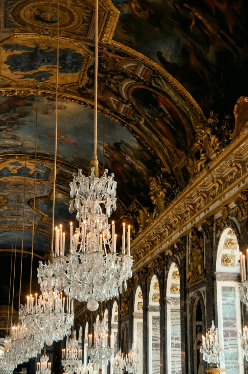 Ornate chandeliers and mirrors inside the Hall of Mirrors at Versailles, central to the history of perfume in France.