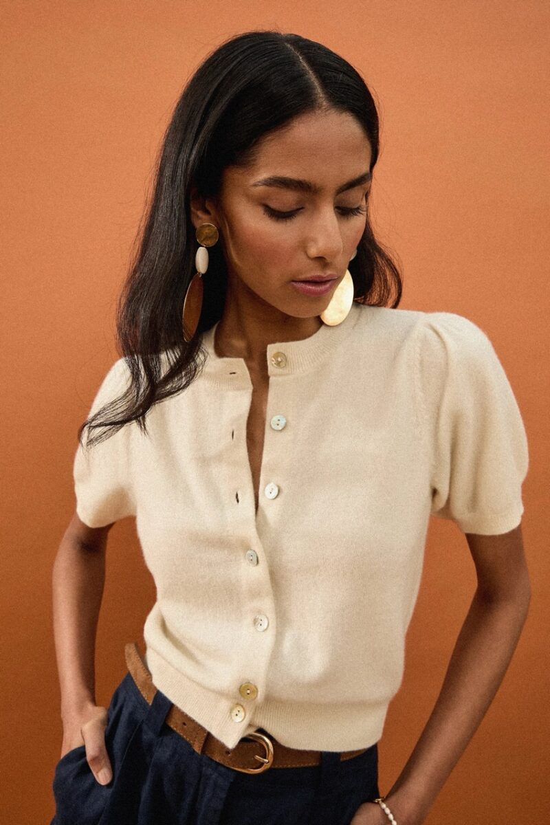 Woman wearing Palome’s cream cashmere cardigan with statement earrings