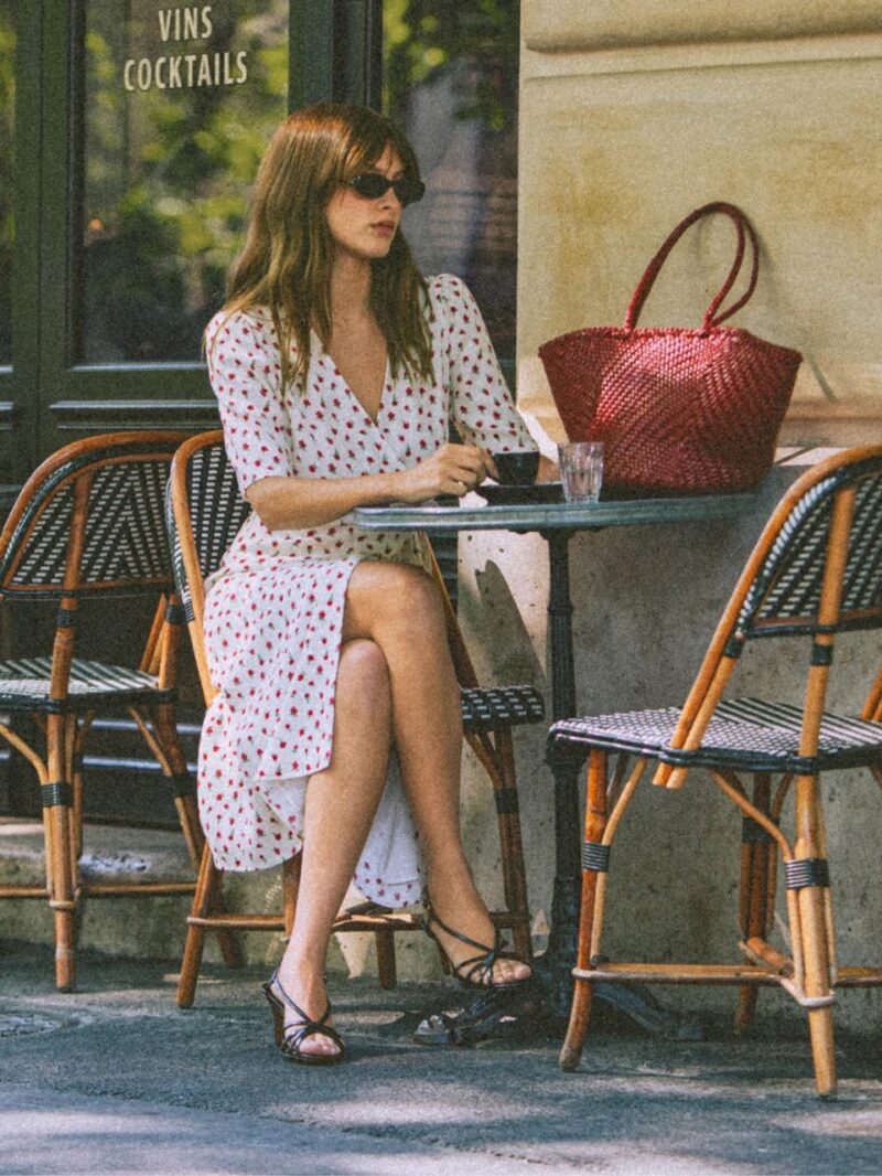 Woman sitting at Paris café in Rouje Gabin wrap dress with cherry print