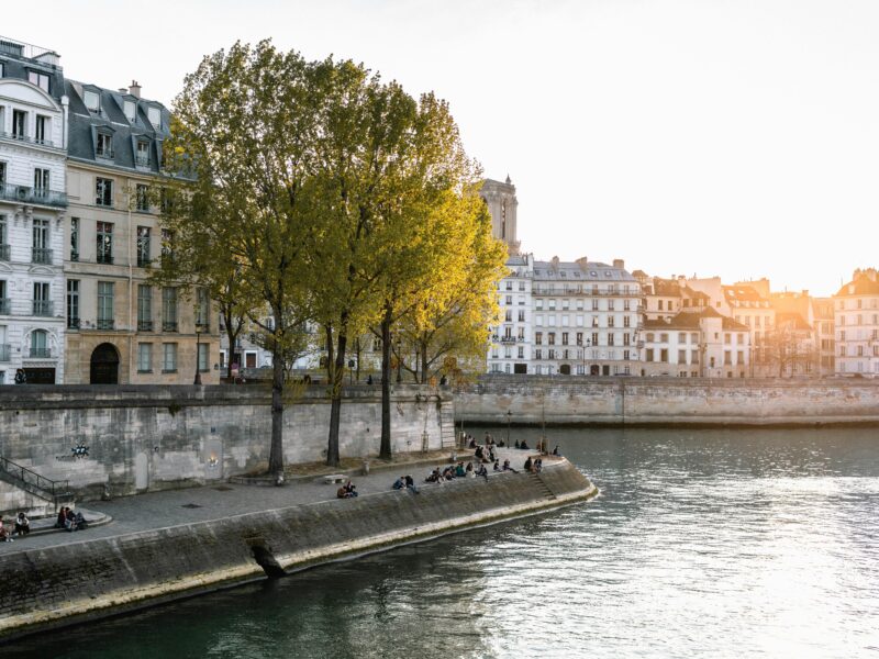 Sunset over the Seine River with people sitting along the bank in Paris