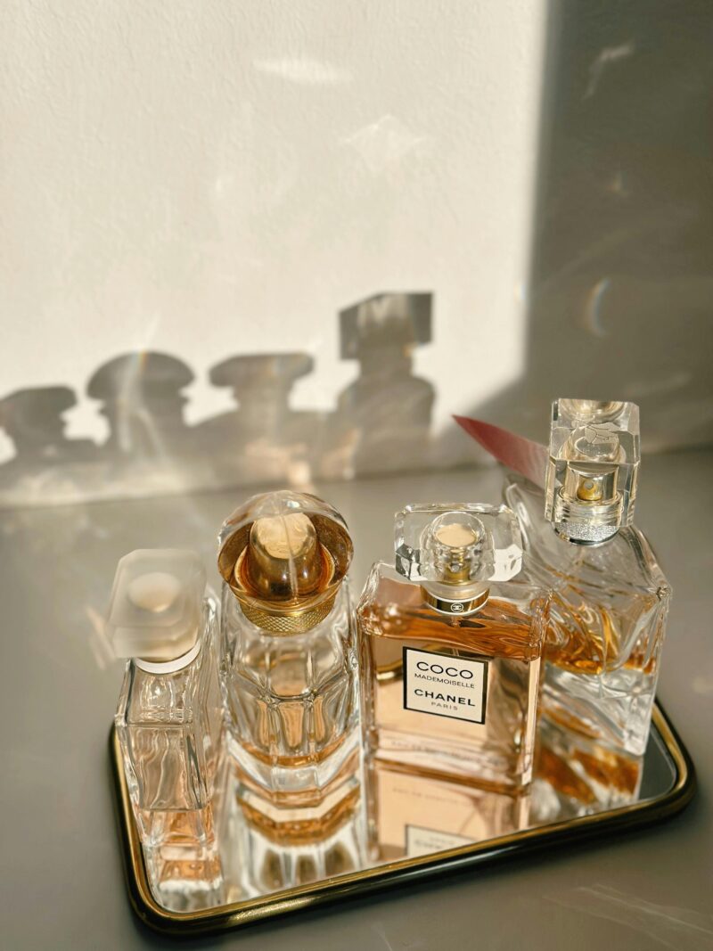 Multiple elegant perfume bottles on a mirrored tray with soft shadows, illustrating perfume layering techniques