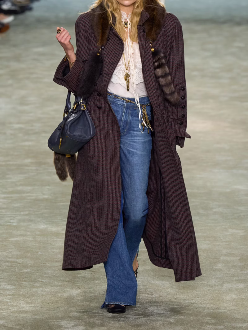 Chloé runway model wearing high-waisted flare jeans, styled with a tailored coat for a Parisian chic look.