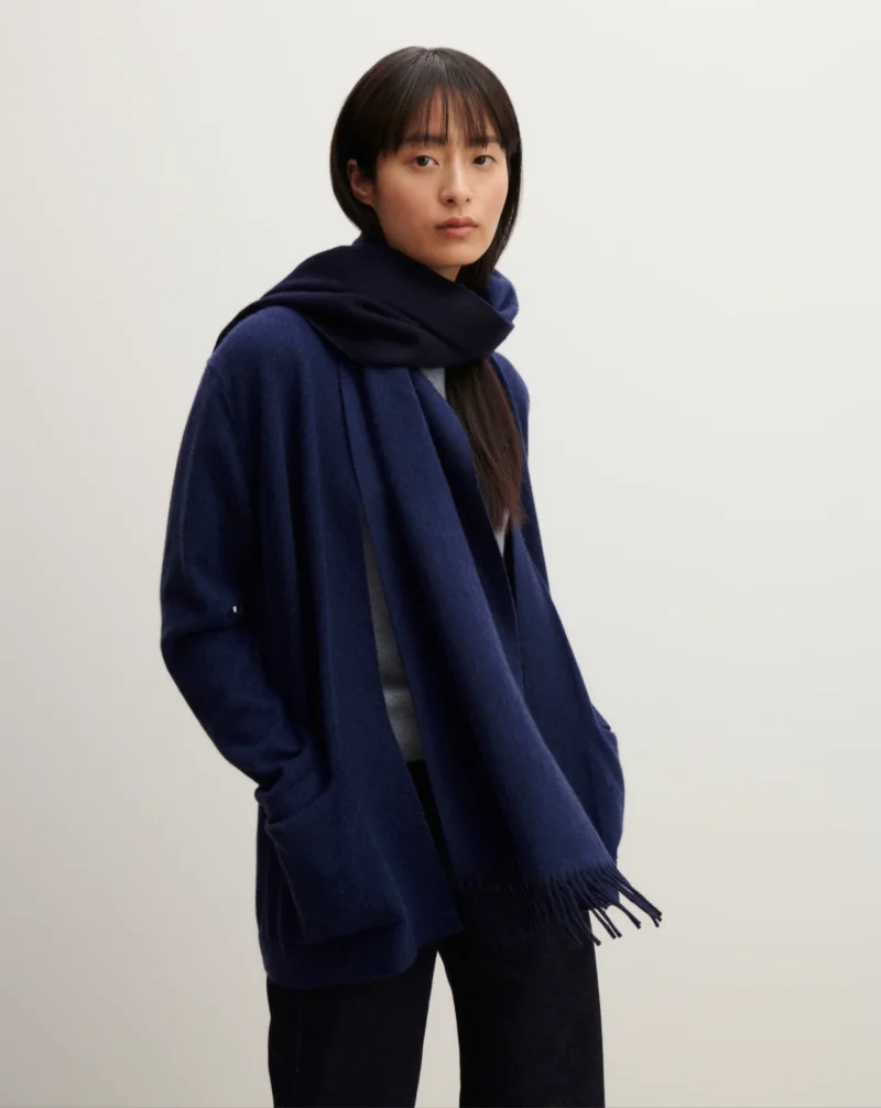 Model wearing a French scarf by Eric Bompard, navy wool scarf draped loosely over a blue cardigan.