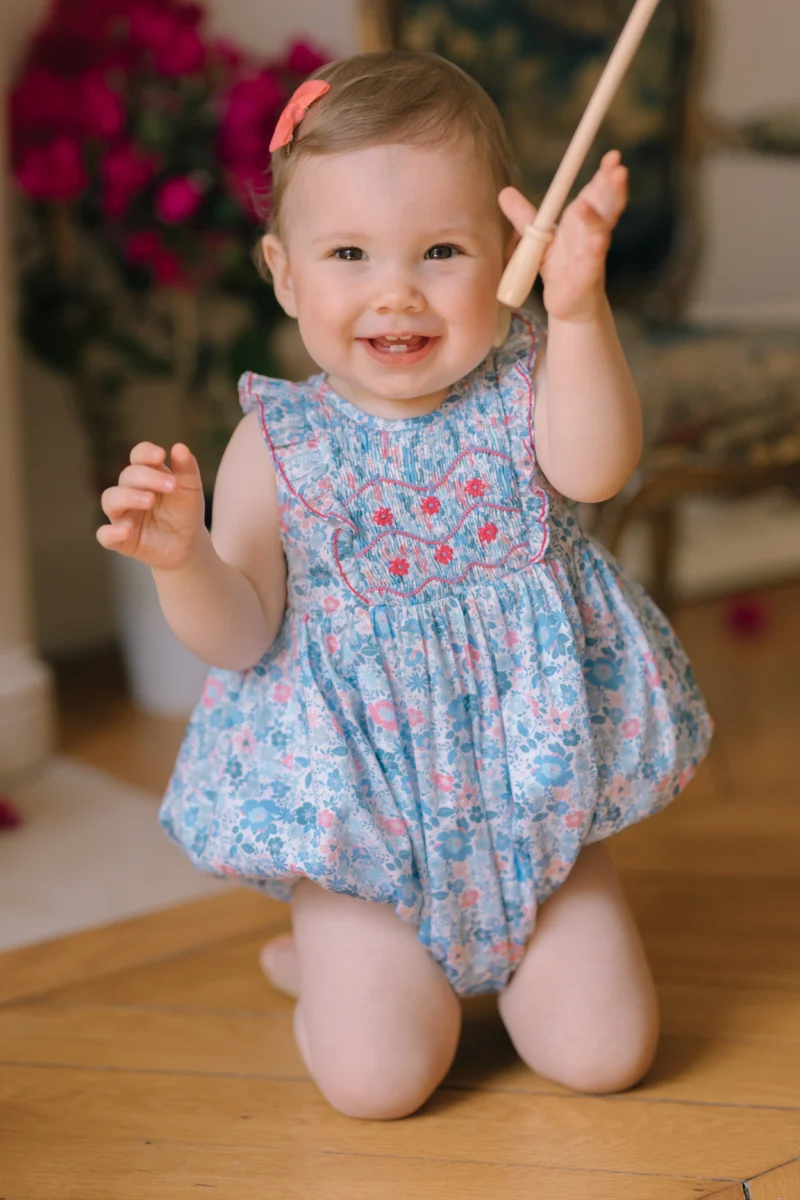 Baby girl in a smocked dress from Antoinette Paris, a luxury French baby clothing brand.