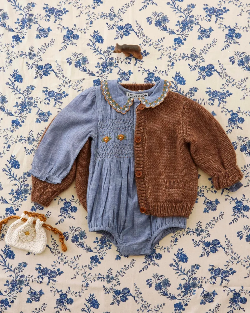 Blue smocked romper with embroidered collar and brown knit cardigan from Emile et Ida